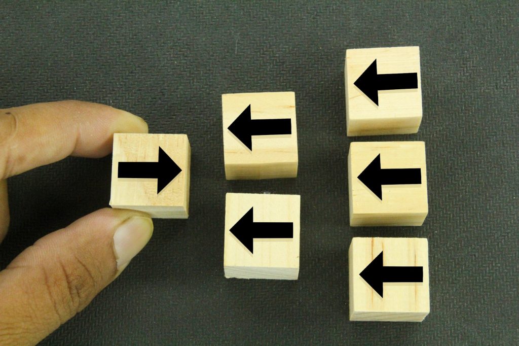 Hand-picked wooden block with arrow pointing in the opposite direction of the black arrow
